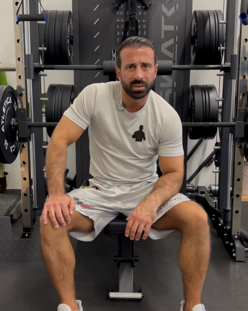 Rocky Siciliano sitzt auf einer Trainingsbank vor einem Hantelrack